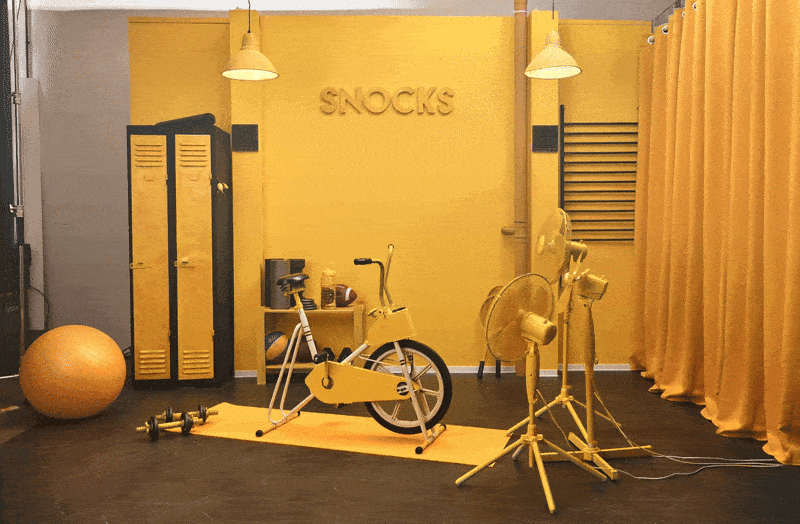 Set design for the Snocks Black Friday campaign featuring a monochromatic yellow studio space with props and brand elements GIF